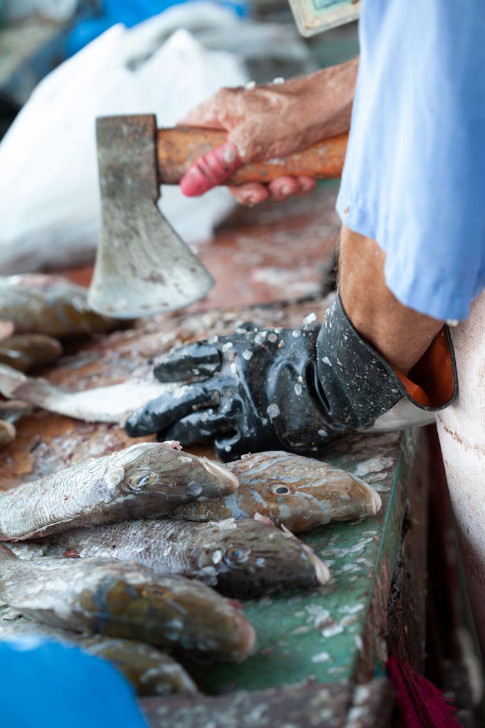 Close-up of a fishmonger preparing fish with axe at Doha market.